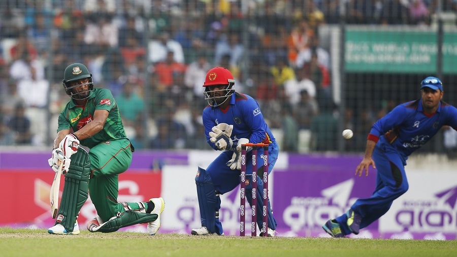 Bangladesh's Mahmudullah, left, plays a shot, as Afghanistan's wicketkeeper Mohammad Shahzad, center, watches and Mohammad Nabi follows the ball during the second one-day international cricket match in Dhaka, Bangladesh, Wednesday, Sept. 28, 2016. (AP Photo/A.M. Ahad)