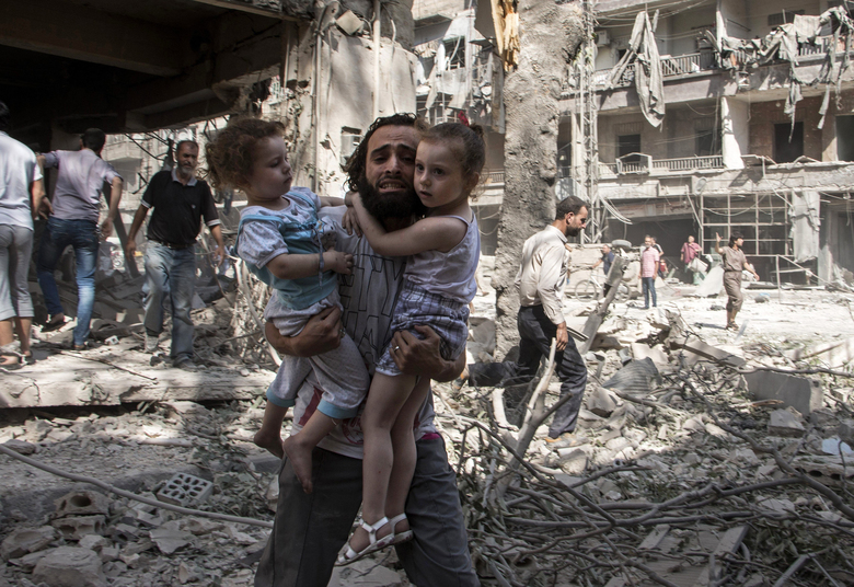 A Syrian man carries his two girls as he walks across the rubble following a barrel bomb attack on the rebel-held neighbourhood of al-Kalasa in the northern Syrian city of Aleppo on September 17, 2015. Once Syria's economic powerhouse, Aleppo has been ravaged by fighting since the rebels seized the east of the city in 2012, confining government forces to the west. AFP PHOTO / KARAM AL-MASRI        (Photo credit should read KARAM AL-MASRI/AFP/Getty Images)