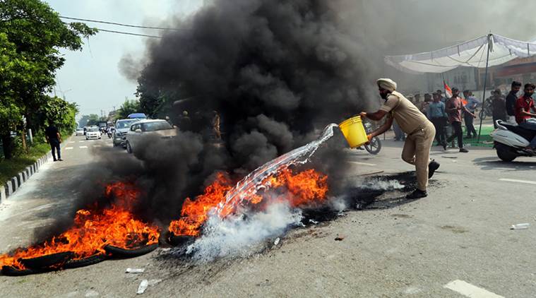 Jammu: A policeman tries to douse a burning tyres during 'Bharat Bandh' protest called by Congress and other parties against fuel price hike and depreciation of the rupee, in Jammu, Monday, Sept 10, 2018. (PTI Photo)(PTI9_10_2018_000106B)