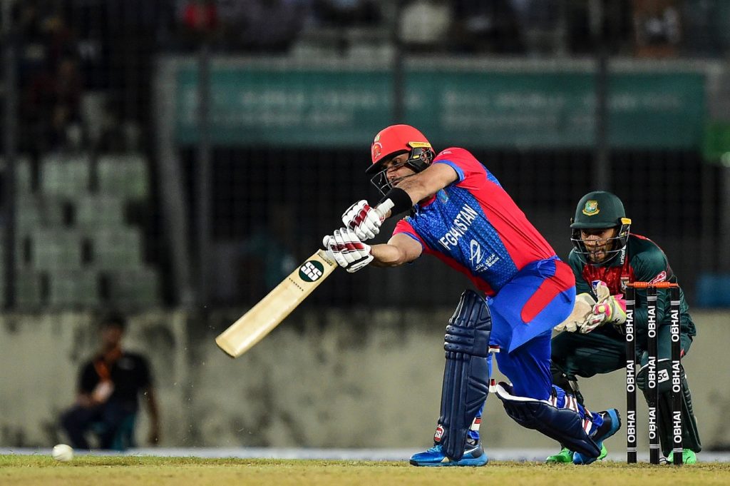 Afghanistan's Mohammad Nabi (L) plays a shot as Bangladesh's Mushfiqur Rahim (R) looks on during the third match between Afghanistan and Bangladesh in the T20 Tri-nations cricket series at the Sher-e-Bangla National Stadium in Dhaka on September 14, 2019. (Photo by MUNIR UZ ZAMAN / AFP)        (Photo credit should read MUNIR UZ ZAMAN/AFP/Getty Images)